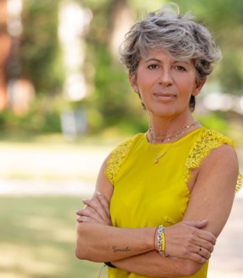Elena Di Stefano, Pixel Studio Productions team member, outdoor portrait in a yellow top with arms crossed